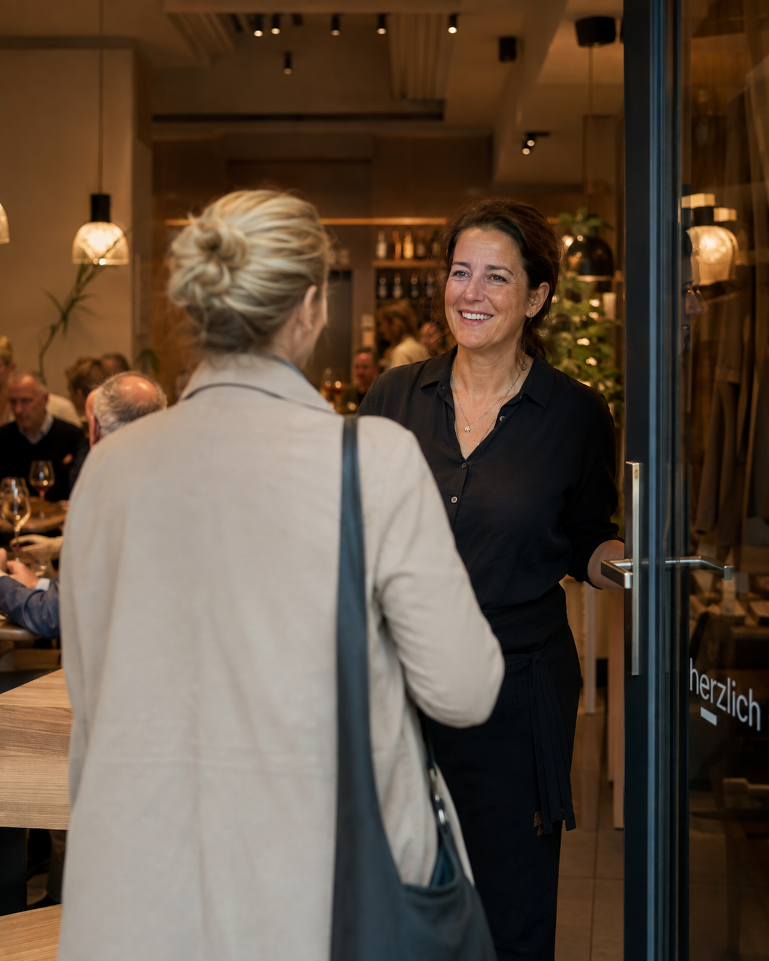 Gastgeberin begrüsst einen wiederkehrenden Gast im Restaurant